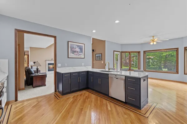 a kitchen with stainless steel appliances a refrigerator a stove a sink dishwasher and white cabinets with wooden floor