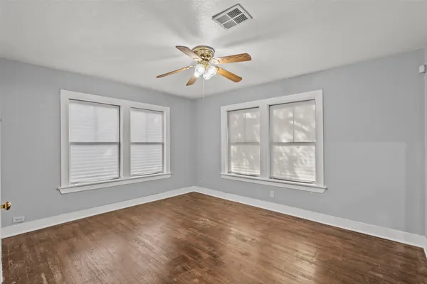 an empty room with windows and fan