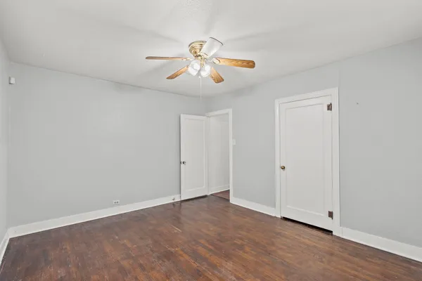 a view of an empty room with wooden floor and window