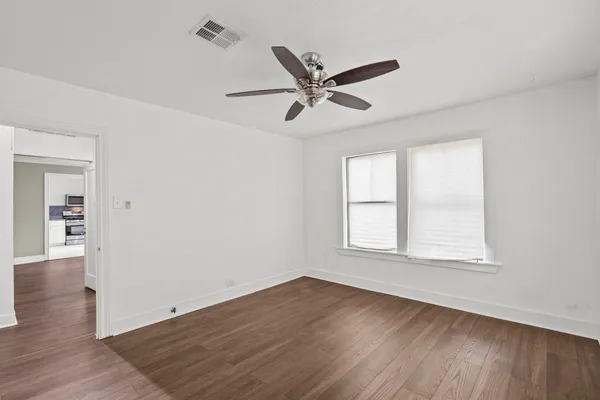 a view of an empty room with wooden floor and a window