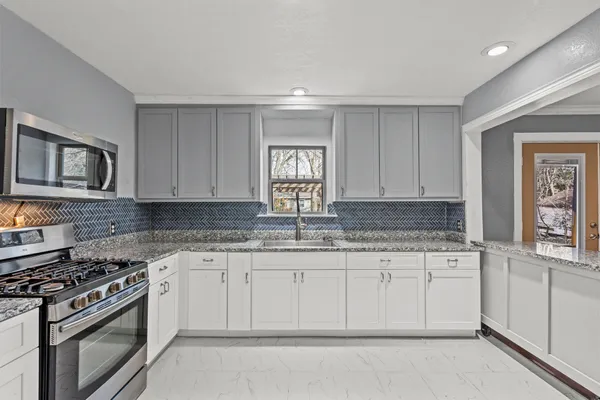 a kitchen with granite countertop a stove sink and cabinets
