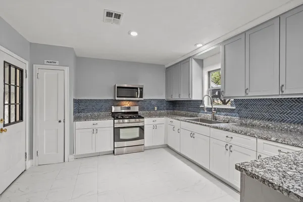 a kitchen with granite countertop a sink stove and refrigerator