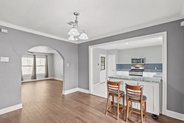 a kitchen with stainless steel appliances granite countertop a stove top oven a sink dishwasher and white cabinets with wooden floor