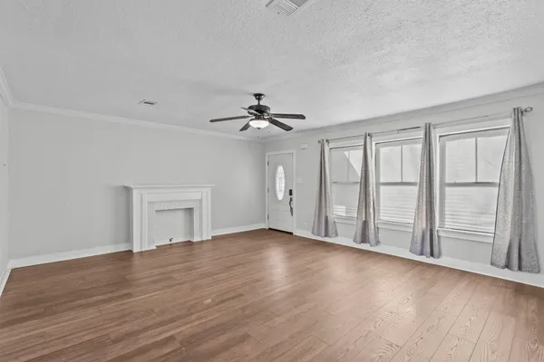 a view of an empty room with a window and wooden floor