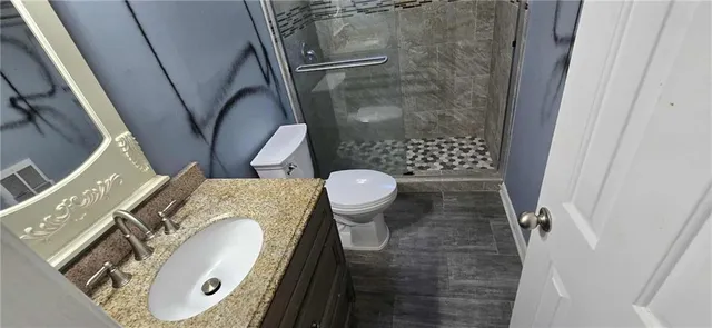 a bathroom with a granite countertop sink toilet and shower