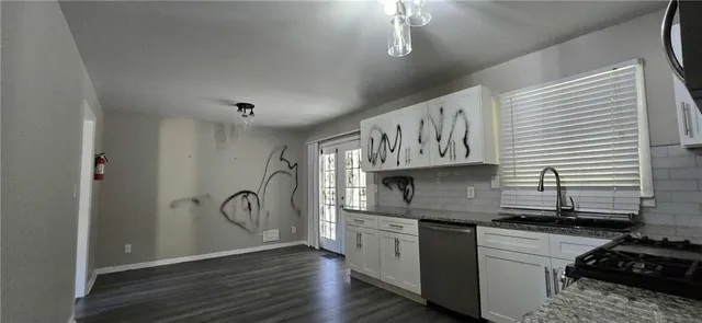 a kitchen with stainless steel appliances granite countertop a sink a stove and wooden floors