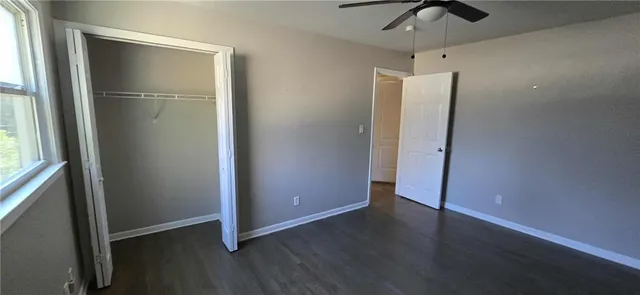 an empty room with wooden floor cabinet and windows