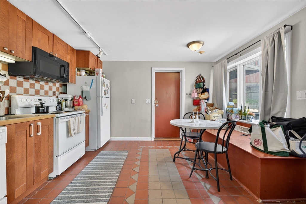 1800 Columbia Road, Unit 6 Boston, MA 02127 - Photo 2 of 11 a kitchen with stainless steel appliances kitchen island granite countertop a table chairs in it and wooden floors