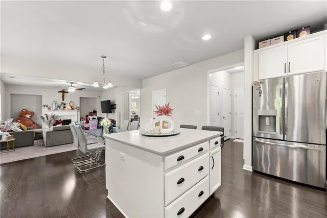 a kitchen with stainless steel appliances granite countertop a refrigerator and a view of living room
