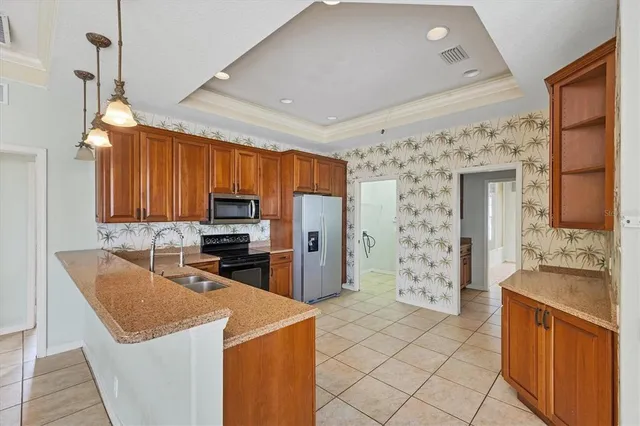 a large kitchen with stainless steel appliances granite countertop a stove top oven a sink dishwasher and a refrigerator