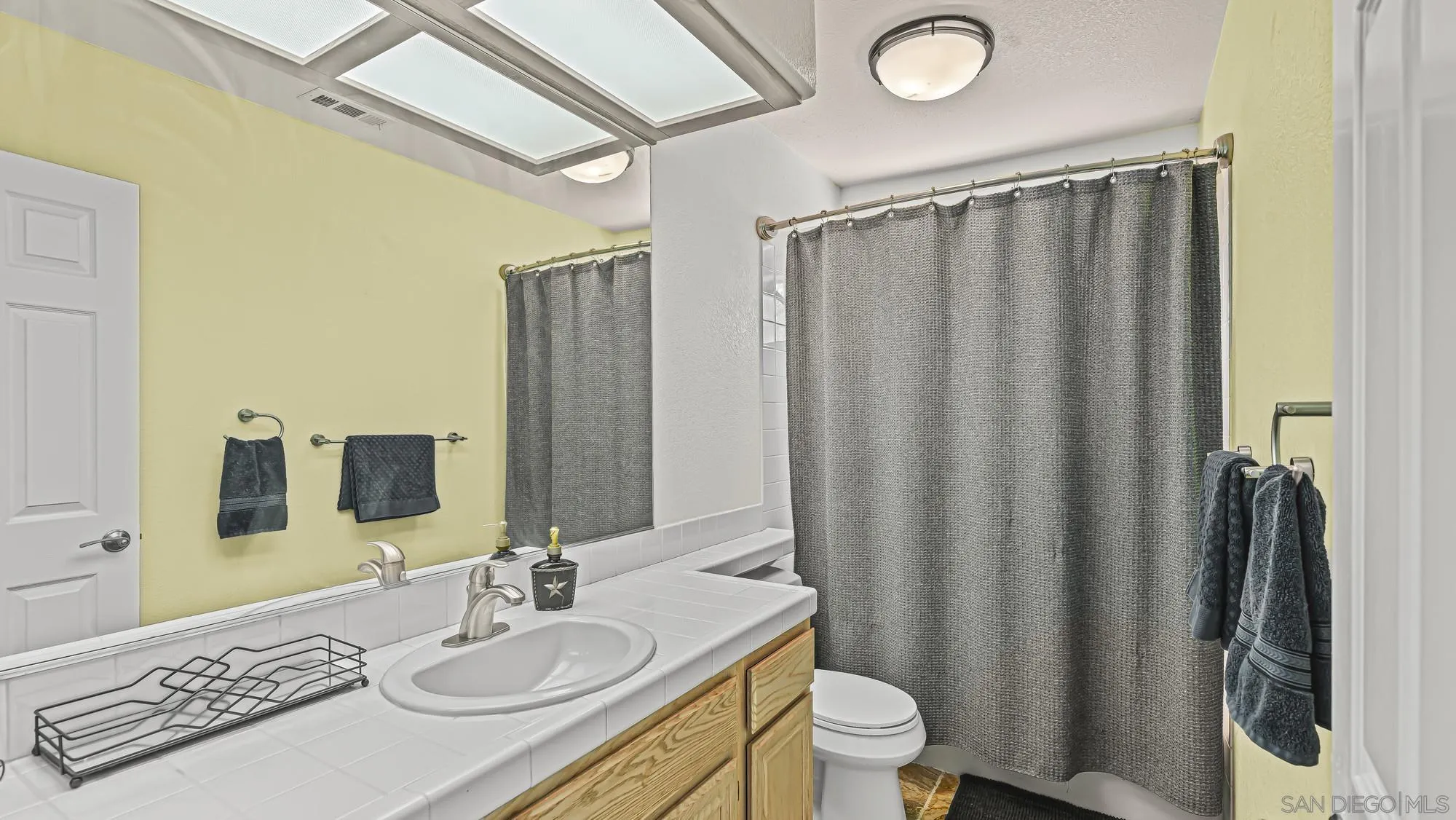 24249 Sargeant Road Ramona, CA 92065 - Photo 23 of 46 a bathroom with a sink a toilet a mirror and shower curtain
