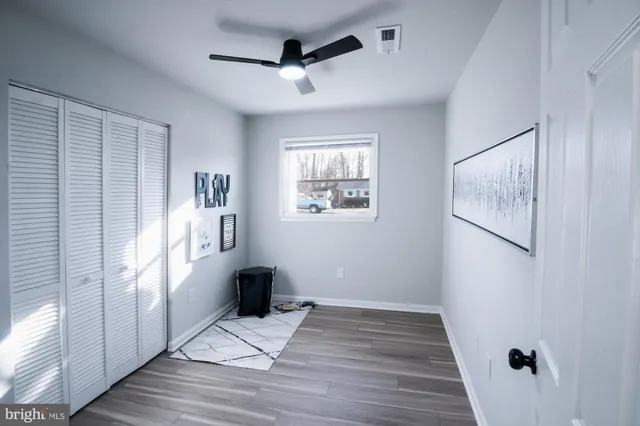 a view of empty room with wooden floor and fan