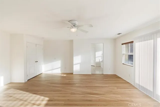 a view of empty room with wooden floor and fan