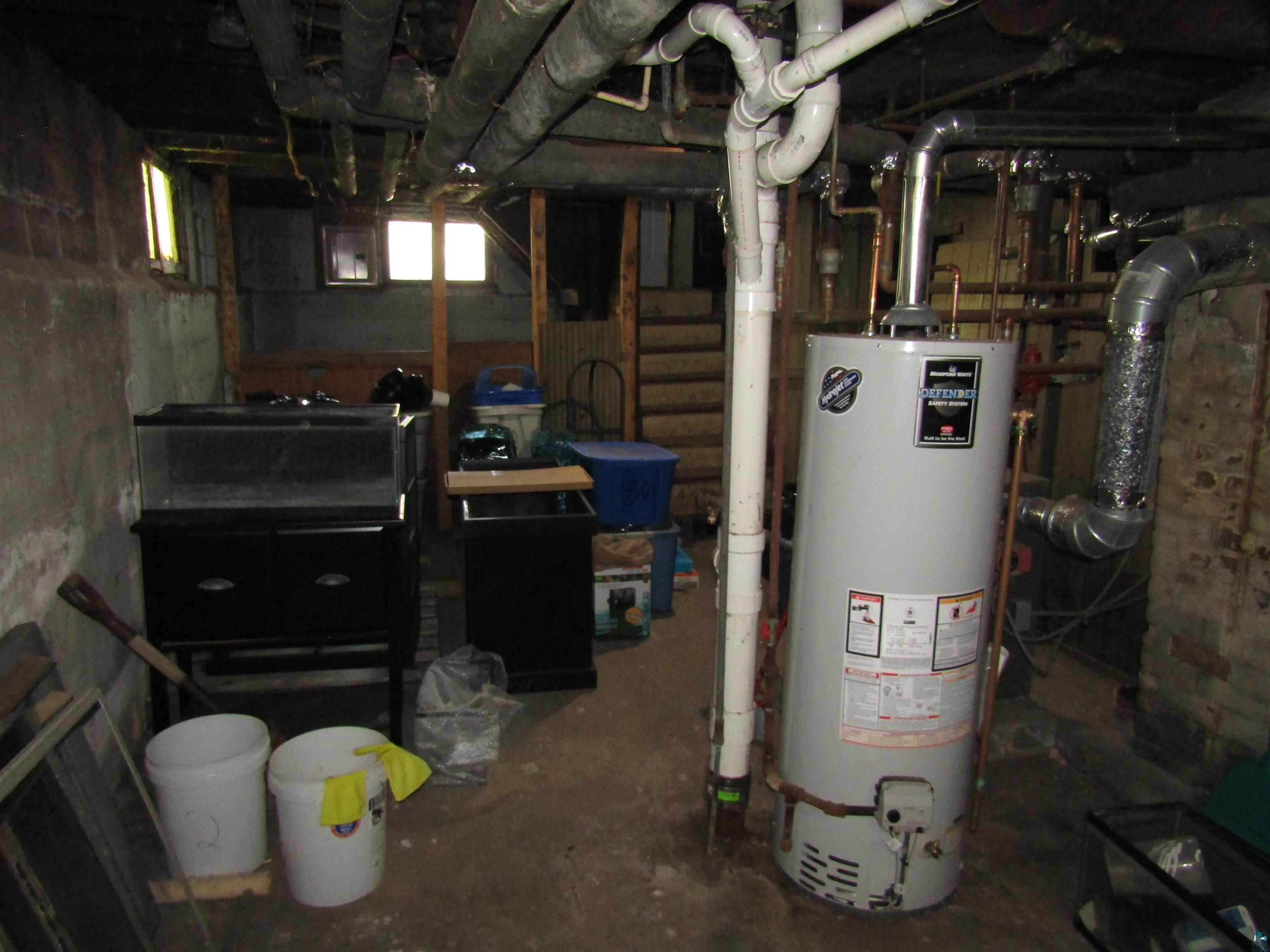 1115 Harrison Street Superior, WI 54880 - Photo 45 of 49 Basement area featuring a water heater, exposed utility piping, concrete block walls, and small windows providing ambient light