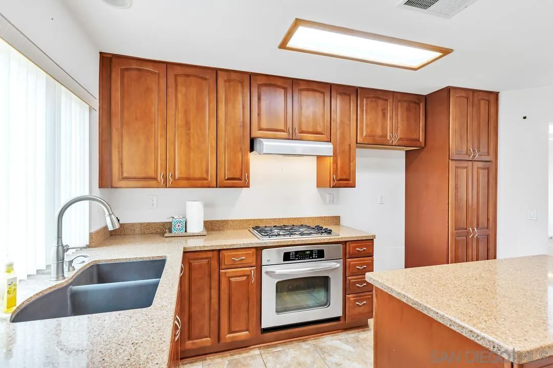 117 Willow Pond Road Santee, CA 92071 - Photo 13 of 49 a kitchen with granite countertop wood cabinets stainless steel appliances and a sink