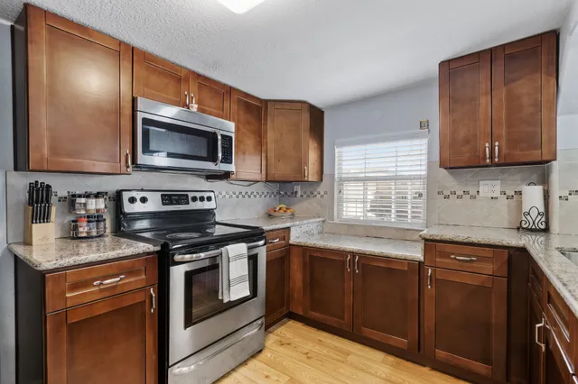 a kitchen with stainless steel appliances granite countertop wooden cabinets stove top oven and sink