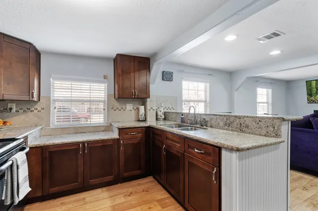 a kitchen with granite countertop sink stove and cabinets