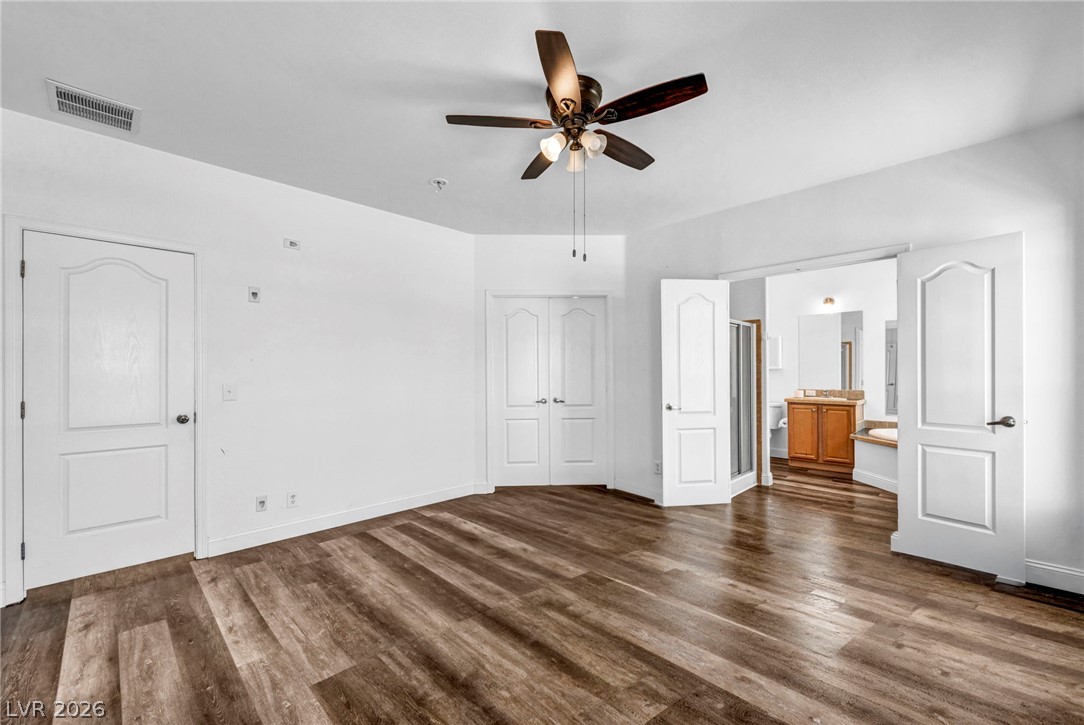 225 California Street Searchlight, NV 89046 - Photo 47 of 64 A roomy bedroom with wood-look flooring and a ceiling fan offers direct access to a well-appointed primary bathroom.