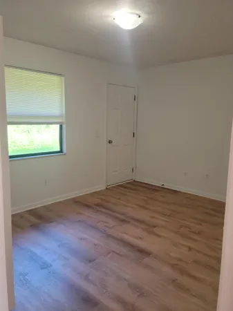 an empty room with wooden floor and a window