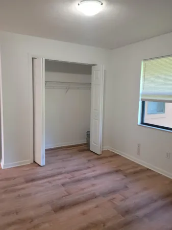 a view of an empty room with wooden floor and closet