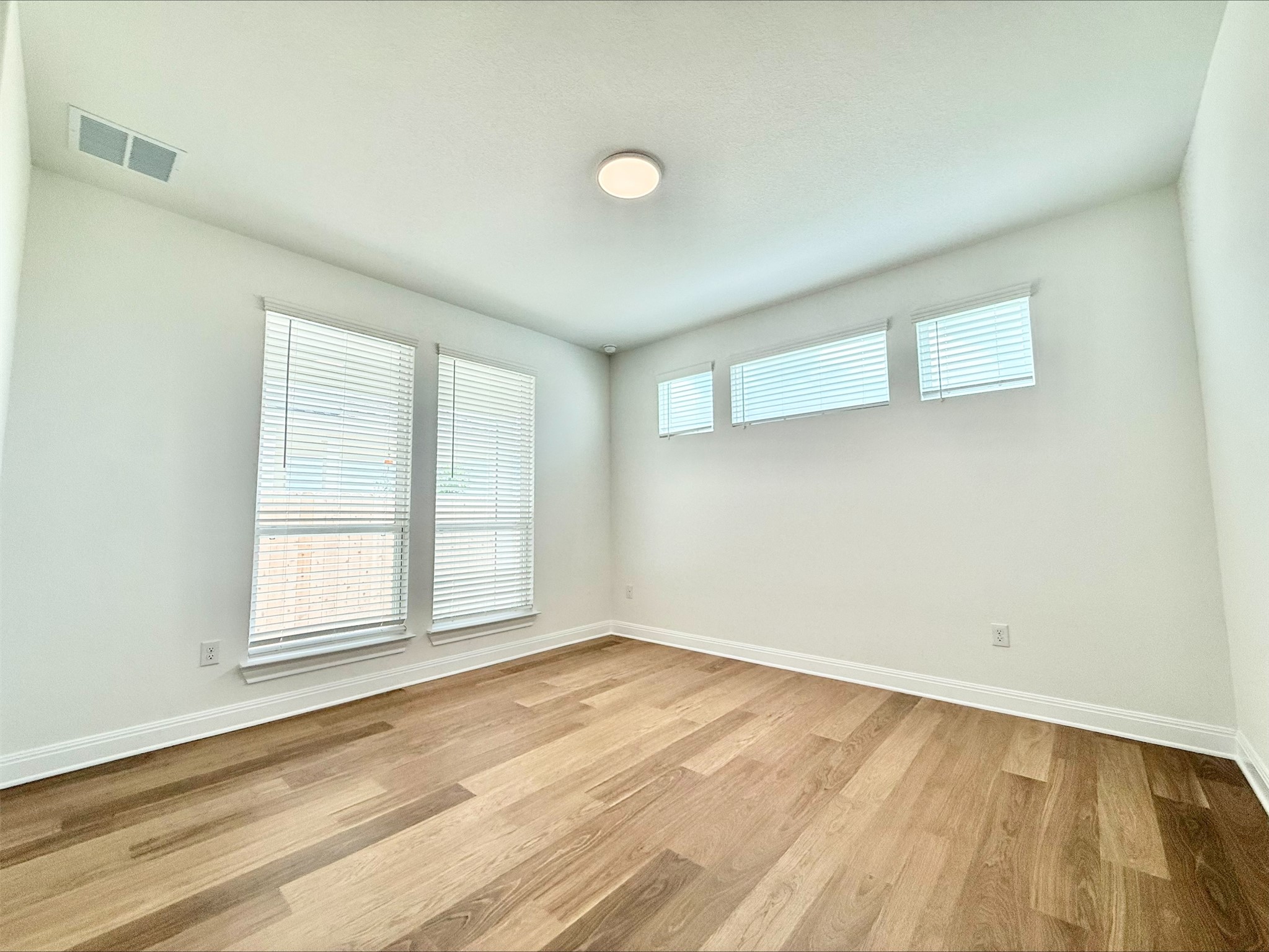 405 Young Street Buda, TX 78610 - Photo 7 of 25 an empty room with wooden floor and windows