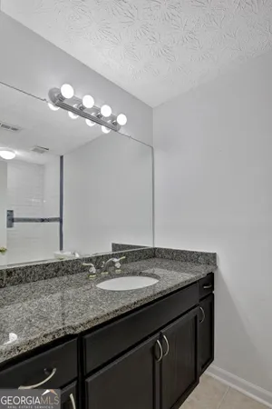 a bathroom with a granite countertop sink and a mirror