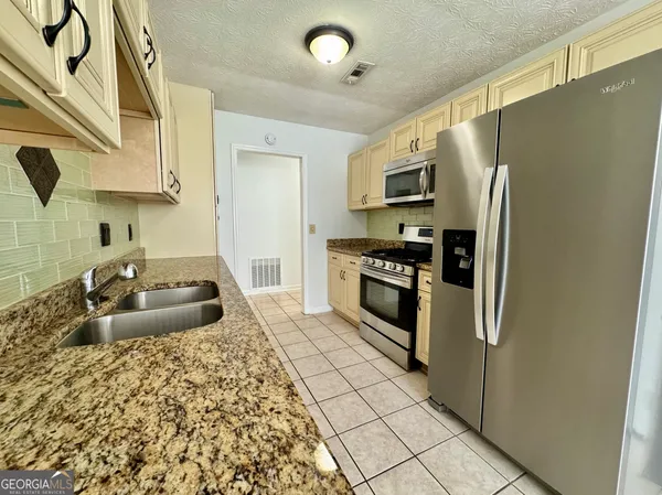 a kitchen with granite countertop a sink stove and refrigerator