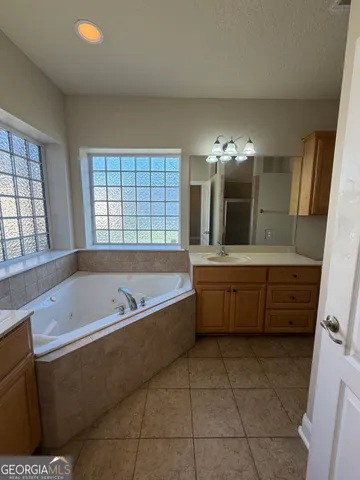 a spacious bathroom with a tub sink and mirror
