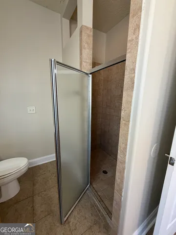 a bathroom with a granite countertop shower and a toilet