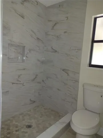 a white toilet next to a shower