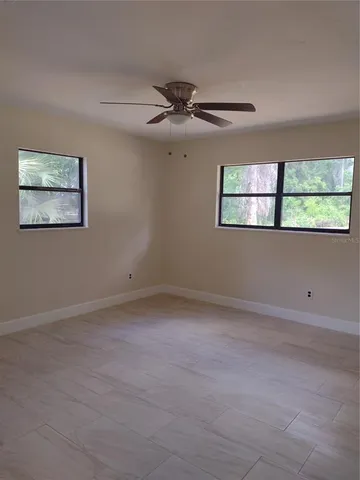 an empty room with windows and fan