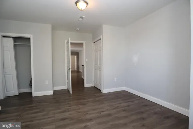 an empty room with wooden floor & closet area