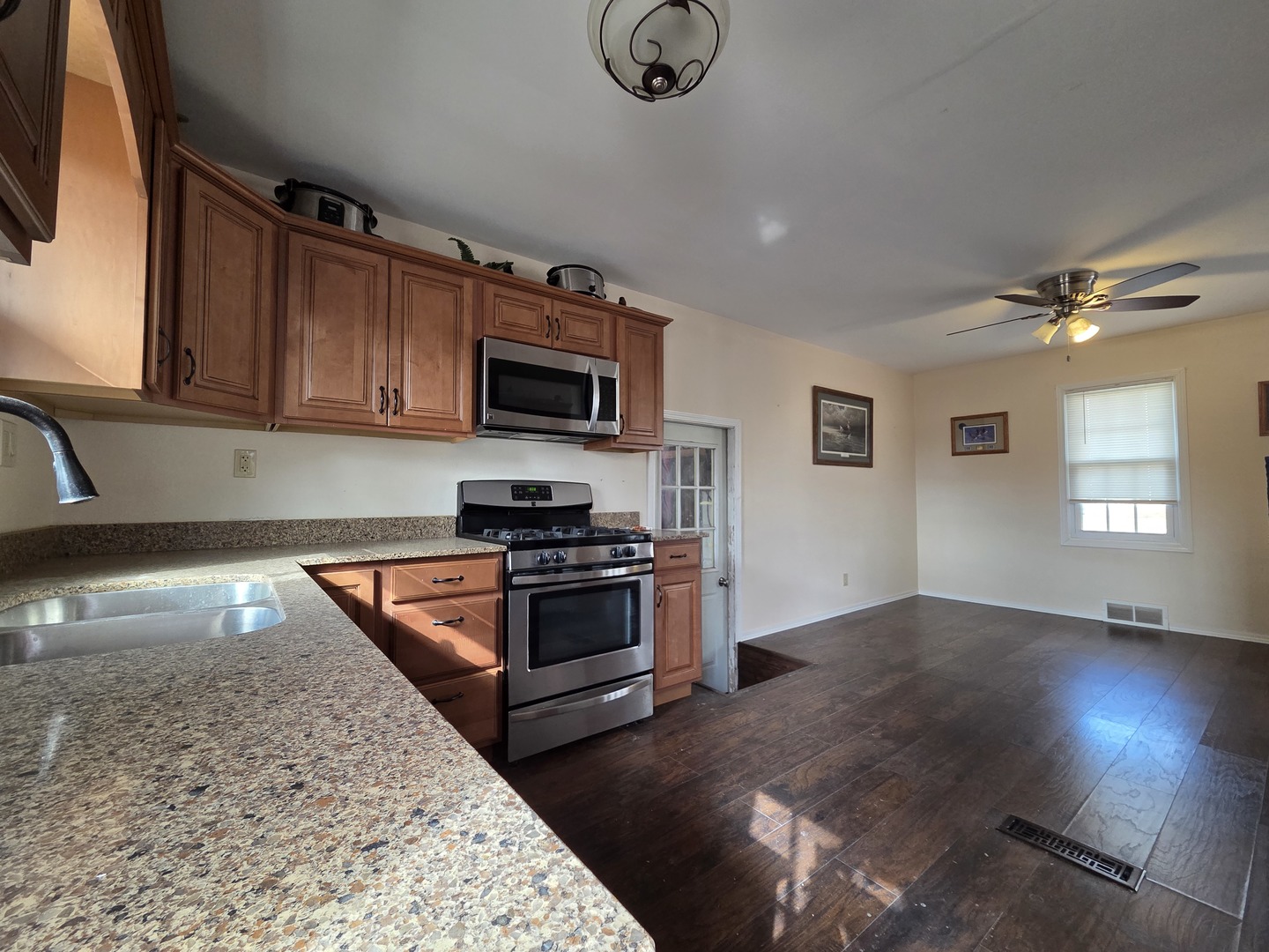 1419 5th Street Camanche, IA 52730 - Photo 5 of 14 a kitchen with granite countertop a stove top oven a sink dishwasher a dining table and chairs with wooden floor
