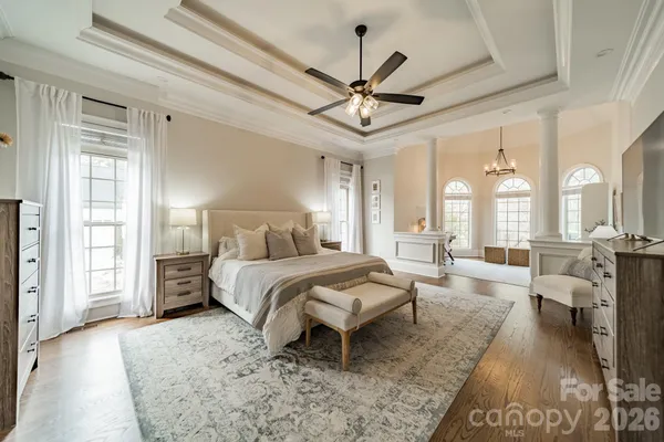 a spacious bedroom with a large bed a chandelier and windows