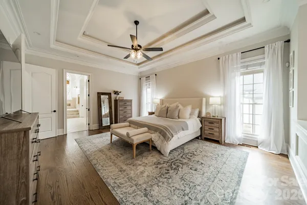 a spacious bedroom with a bed a ceiling fan and a wooden floor