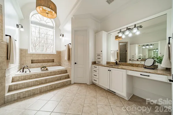 a large white bathroom with a large tub sink and mirror