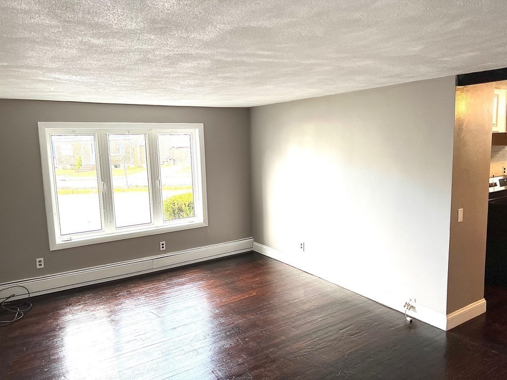 150 Locust Street, Unit 1 Winthrop, MA 02152 - Photo 5 of 11 an empty room with wooden floor and windows with curtains view
