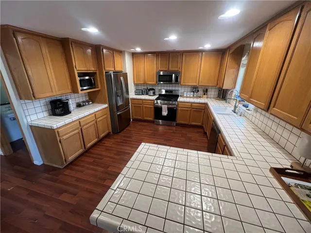 a kitchen with stainless steel appliances a sink a stove top oven a refrigerator and cabinets