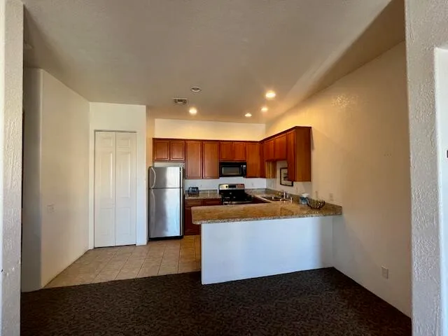 a kitchen with stainless steel appliances granite countertop a refrigerator a sink dishwasher a stove with white cabinets