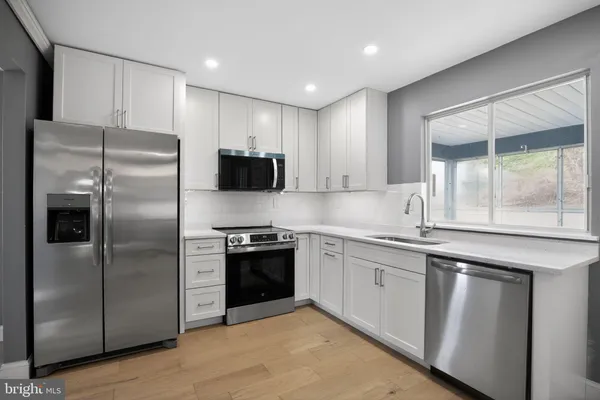 a kitchen with stainless steel appliances granite countertop a refrigerator a sink a stove and cabinets