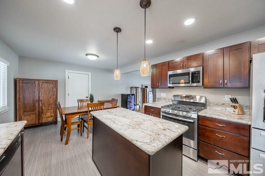 1640 Davidson Way Reno, NV 89509 - Photo 8 of 25 a kitchen with stainless steel appliances granite countertop a stove top oven a sink a dining table and chairs with wooden floor