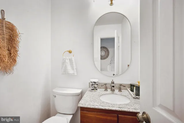 a bathroom with a granite countertop sink mirror vanity and toilet