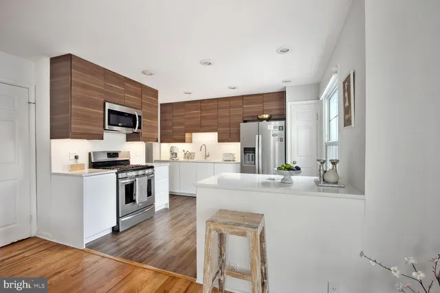 a kitchen with stainless steel appliances granite countertop a stove top oven a sink a dining table and chairs with wooden floor