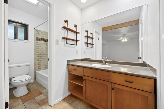 a bathroom with a granite countertop sink toilet and mirror