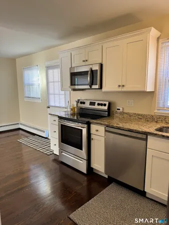 a kitchen with stainless steel appliances granite countertop a stove a sink and white cabinets