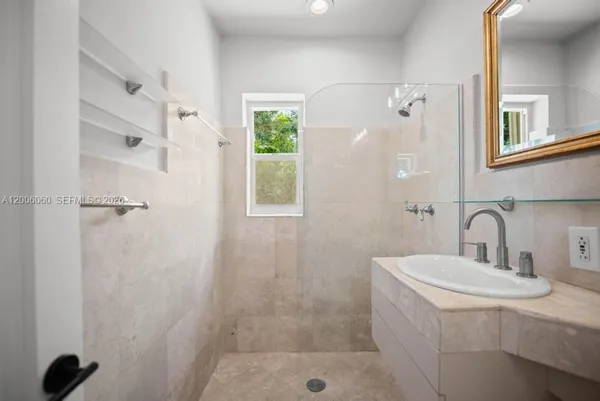 a bathroom with a sink shower and a mirror