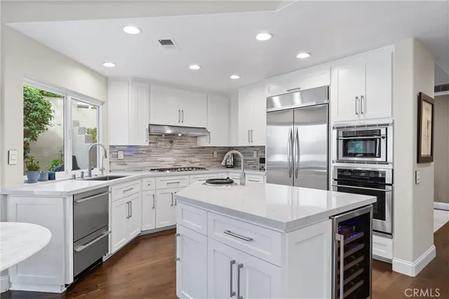 a kitchen with a dining table chairs wooden floor appliances and cabinets