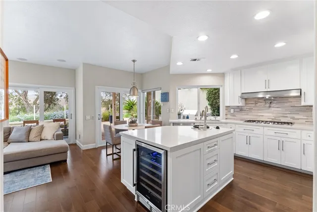 a kitchen with kitchen island granite countertop a sink and white cabinets with wooden floor