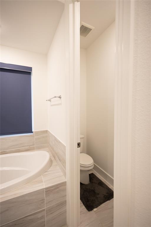 3017 Andorra Road McKinney, TX 75071 - Photo 21 of 40 Soaking tub with tile surround, partial wall, and recessed toilet area