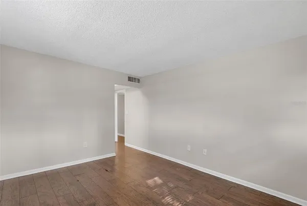 a view of an empty room with wooden floor and closet